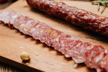 Sliced sausage with pistachios on wooden board, ideal for food presentations and gourmet displays