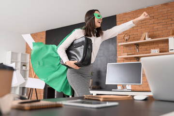Businesswoman dressed as superhero with briefcase in office