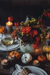 Beautiful seasonal decorated Thanksgiving table for cozy family dinner or fall luxury countryside wedding. Elegant beautiful setting for holiday event, party, reception. Wineglasses and fancy dishes. 