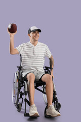 Sporty young man in wheelchair with rugby ball on lilac background