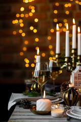 Elegant decor for Christmas family dinner. Center piece with burning candles, vintage chandelier. Zero waste eco-friendly reusable home decoration, fir tree branches. Cozy atmosphere, wooden furniture