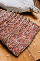 Close-up of sliced dry-cured salami on board, ideal for gourmet food and charcuterie presentations