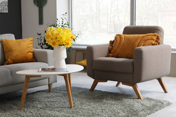 Grey sofa, armchair, plaid and coffee table in stylish living room