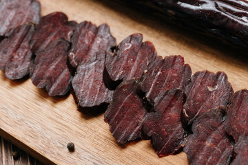 Sliced dark cured sausage on board, highlighting deep color and rich texture for gourmet appeal