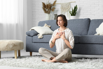Young woman meditating while sitting on floor at home