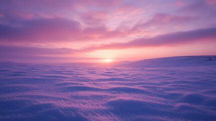 A sunset over a snowy landscape with the snow reflecting the soft pinks and purples of the sky and the air crisp and cold.