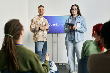 Group of people engaging in QA session during conference event with presenters standing in front...