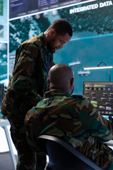 Military staff in a modern operations hub handling critical information collected on satellite systems, real time data helping support field missions. Army protocols vital for national security.