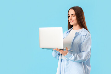 Young beautiful woman using laptop on blue background