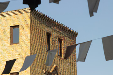 A vibrant summer scene featuring the corner of an industrial brick building under a bright blue...