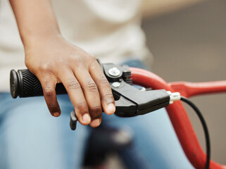 Child, bike and hand on brake outdoor with park, riding and fun activity for childhood memory. Person, kid and bicycle lever for stop, safety and reduce speed on weekend for game, play and learning