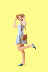 Young pretty woman in hat on yellow background
