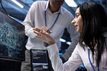 Coworkers using AI tech to fix errors in server farm providing storage. IT staff members in data...