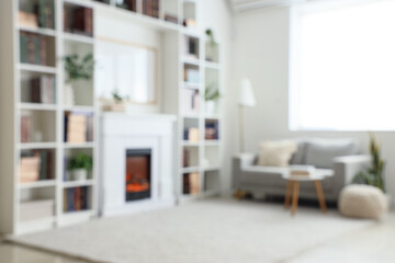 Interior of modern home library with bookshelves, sofa, coffee table and fireplace. Blurred view