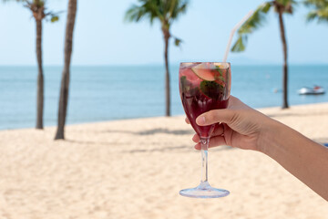 girl is holding a red cocktail at beach