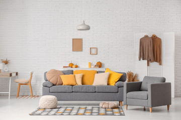 Autumn interior of living room with comfortable sofa and armchair