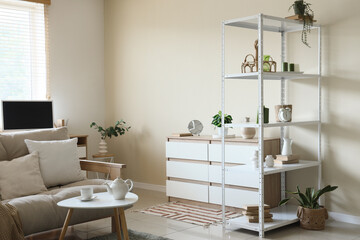 Interior of living room with shelving unit, sofa, coffee table and chest of drawers