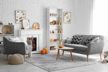 Interior of stylish living room with fireplace, coffee table, sofa and pumpkins. Autumn concept