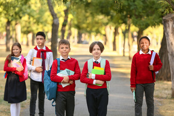 Obraz premium Group of happy pupils with stationery going to school outdoors
