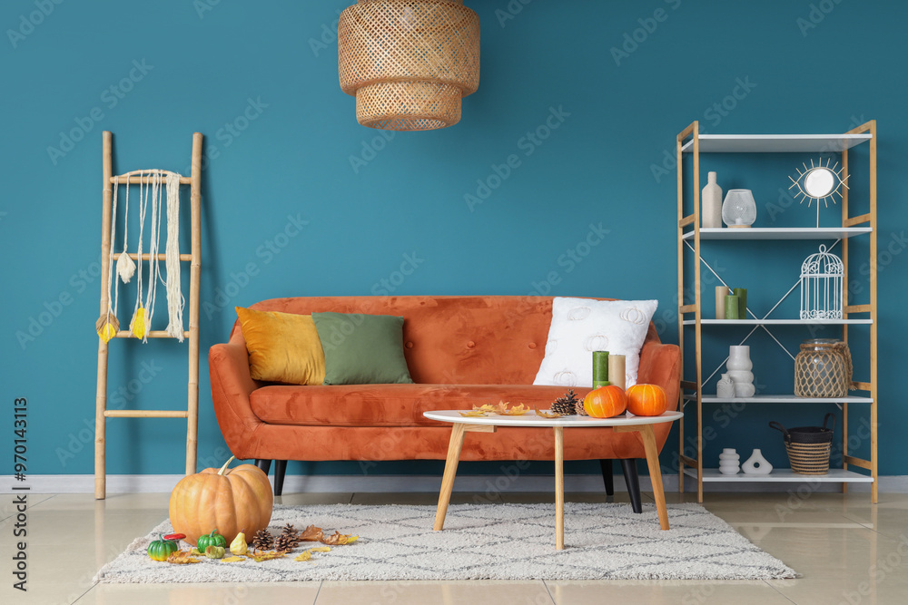 Wall mural Cozy sofa, coffee table with pumpkins and autumn decor in interior of living room