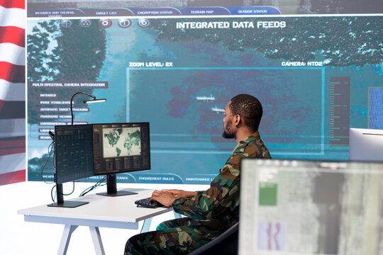 Military officer in a high tech control center engages in cybersecurity operations, protecting classified data from cyber threats and managing digital warfare strategies to maintain state secrets.