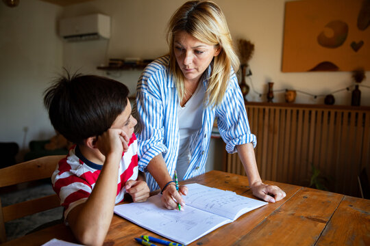 Mother helping son with homework at kitchen table