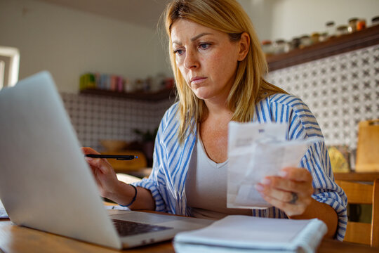Woman feeling stressed while reading bills at home