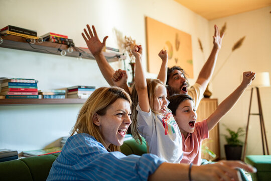 Family celebrating victory while watching sports on TV at home
