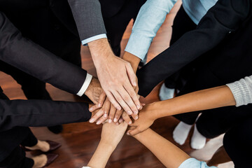 Multiracial business people make synergy hand stack together in meeting room as cooperation or team building for corporate employee in workplace. Meticulous