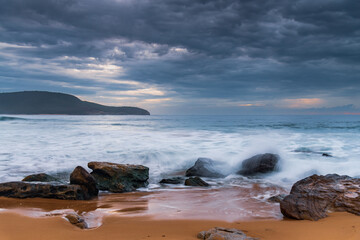 Sunrise at the seaside with rocks and beautiful diffused light by the rain clouds