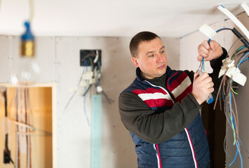 Repair man working on electric wires during reconditioning works in apartment.