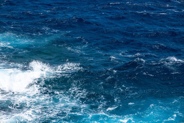 Photograph of the sea with waves and foam breaking against the shore. Concept: Holidays, lifeguard, fishing, maritime.