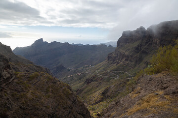 A recognisable mountain pass in the middle of nowhere with a rural village in the background. Concept: Pass, rural, mountain road.