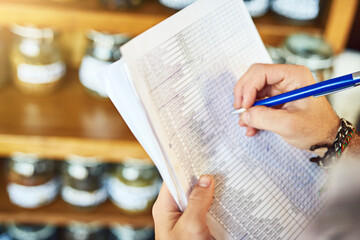 Hands, shop owner and writing with document in cafe with review for inventory, stock and ingredients. Person, paperwork and checklist with notes by shelf for coffee, tea and stats at restaurant