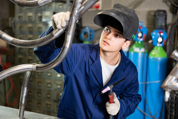 Young male metallurgist working with welding machine in metallurgical workshop