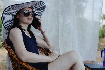 Portrait of a young woman talking on a mobile phone in the garden.