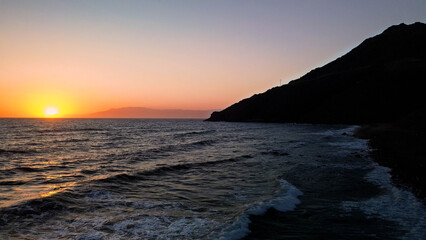 Fototapeta premium Perched high above the crashing waves the lighthouse watches over the endless blue horizon of the sea 