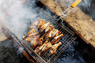 BBQ chicken legs roasting on coals in the garden.