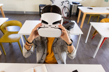 Using VR headset, asian teenage boy exploring virtual reality in school classroom