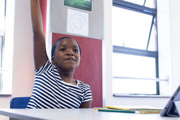 In school, african american girl raising hand in classroom, eager to answer question