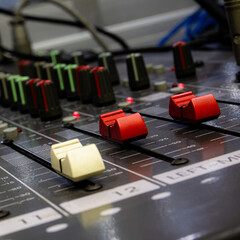 Professional analog audio mixing console with knobs and slides for music and recording equipment,Blurred background and close-up.