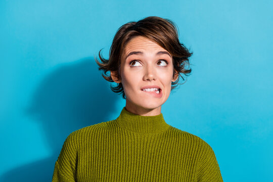Photo of worried nervous girl wear khaki clothes look up empty space biting lips oops problem trouble isolated on cyan color background