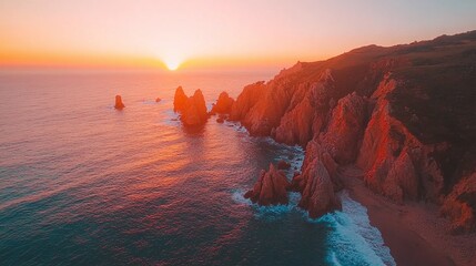 Sunset over rugged coastal cliffs and ocean waves, casting a warm orange glow. Perfect for travel...