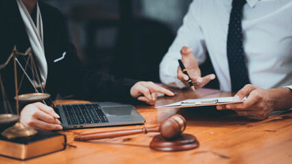 Professional lawyers in a business meeting reviewing legal documents with a gavel and scales of justice on the table.