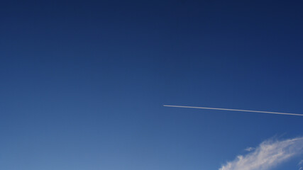 Chemtrail from a jet in clear blue sky.
