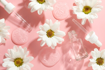 Beautiful daisy flowers, cosmetic bottle, pipettes and drops of serum on pink background, flat lay
