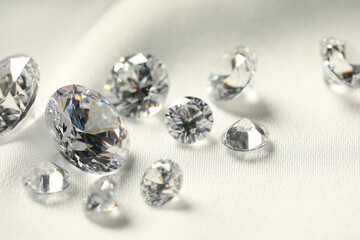Many beautiful shiny diamonds on white fabric, closeup