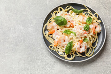 Tasty pasta with shrimps on light grey table, top view. Space for text