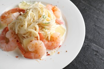 Delicious pasta with shrimps and cheese on black table, closeup