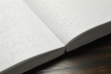 Book with Braille text on wooden table, closeup. Education and leisure for blind people